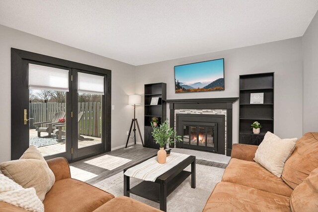 living area with baseboards, a glass covered fireplace, and wood finished floors