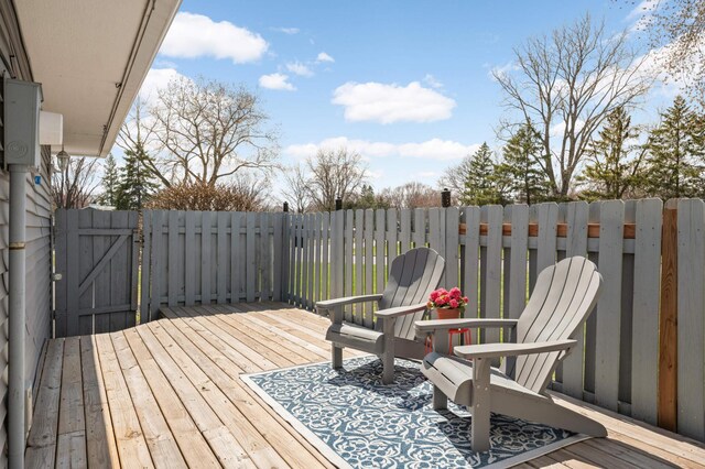 wooden terrace featuring fence and a gate