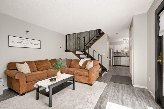 living area featuring baseboards, wood finished floors, and stairs