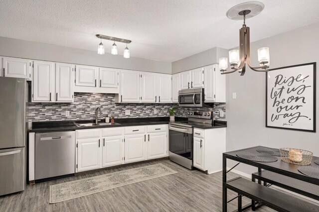 kitchen featuring a sink, dark countertops, backsplash, a chandelier, and appliances with stainless steel finishes