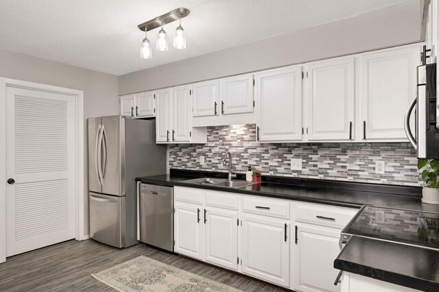 kitchen featuring dark countertops, a sink, white cabinetry, and appliances with stainless steel finishes