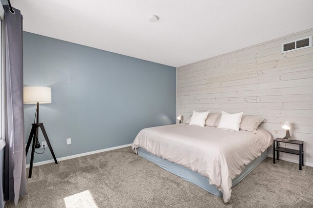 bedroom with visible vents, baseboards, carpet flooring, and wood walls