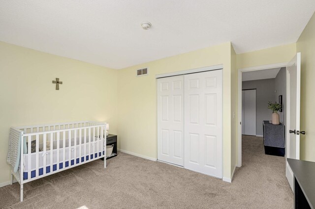 carpeted bedroom featuring baseboards, visible vents, and a closet