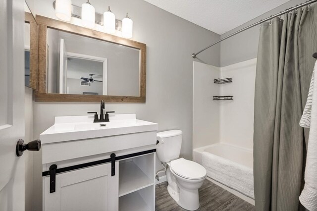 full bathroom with wood finished floors, vanity, shower / bath combination with curtain, ceiling fan, and toilet