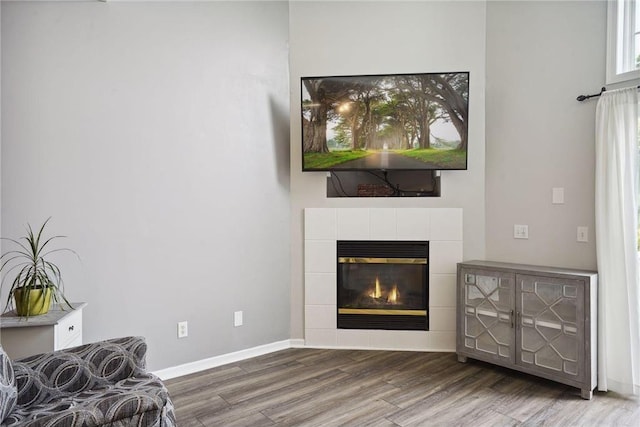 living room featuring a tiled fireplace, wood finished floors, and baseboards
