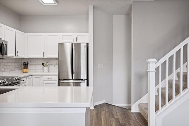 kitchen with dark wood-style floors, backsplash, white cabinets, and appliances with stainless steel finishes