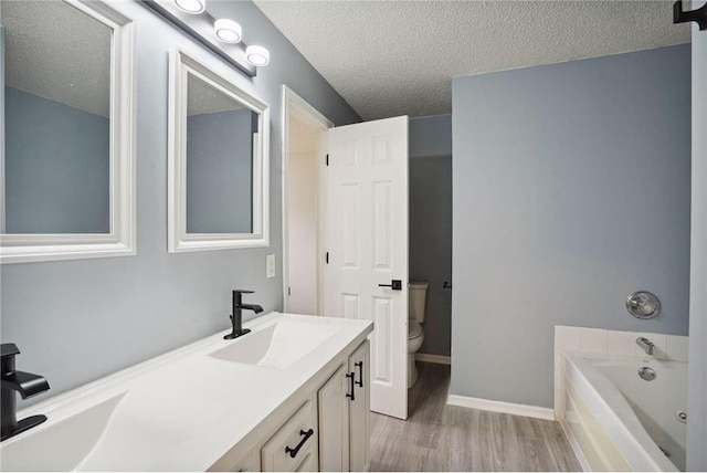 full bath featuring wood finished floors, toilet, a bath, a sink, and a textured ceiling