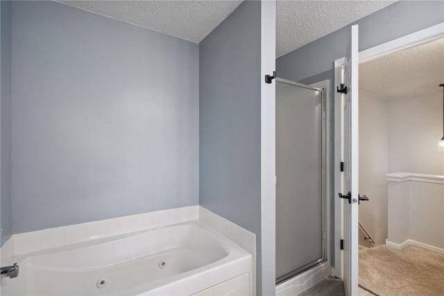 full bath with a tub with jets, a textured ceiling, and a shower stall