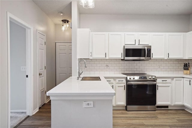 kitchen featuring white cabinets, wood finished floors, appliances with stainless steel finishes, and a sink