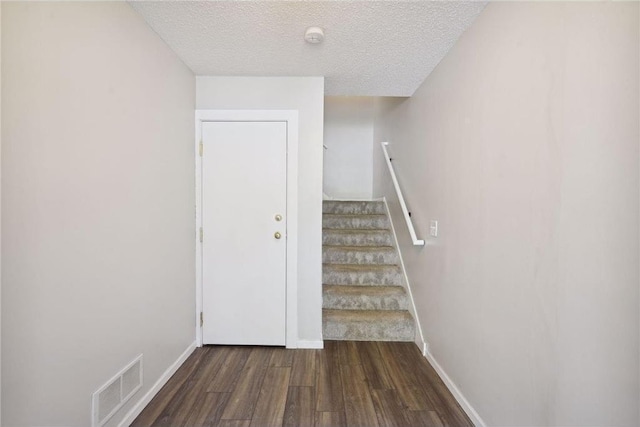 staircase with baseboards, visible vents, wood finished floors, and a textured ceiling