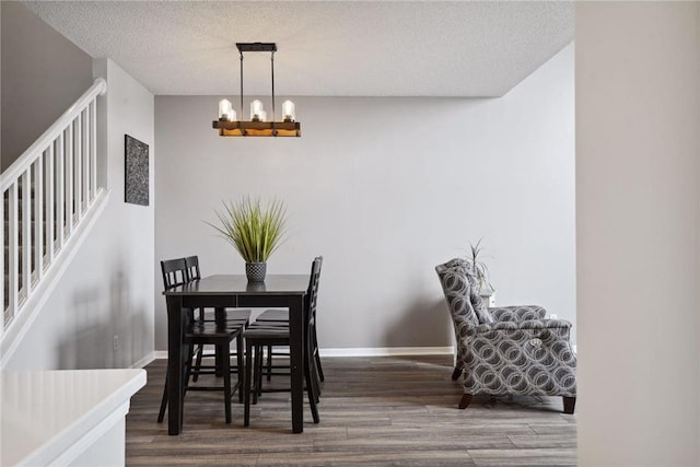 dining room with wood finished floors, a chandelier, baseboards, stairway, and a textured ceiling