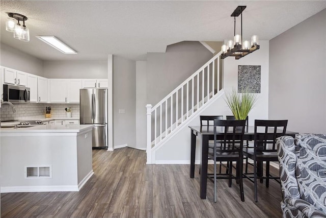 kitchen with dark wood-style floors, a notable chandelier, visible vents, light countertops, and appliances with stainless steel finishes