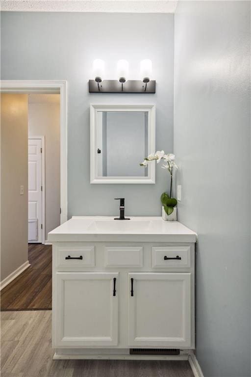 bathroom featuring vanity, wood finished floors, and baseboards