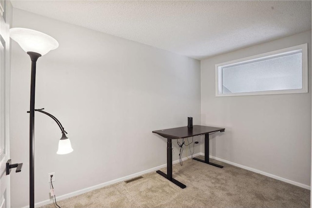unfurnished office with a textured ceiling, visible vents, carpet, and baseboards