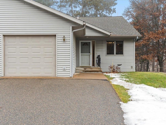 single story home featuring a garage, driveway, and roof with shingles