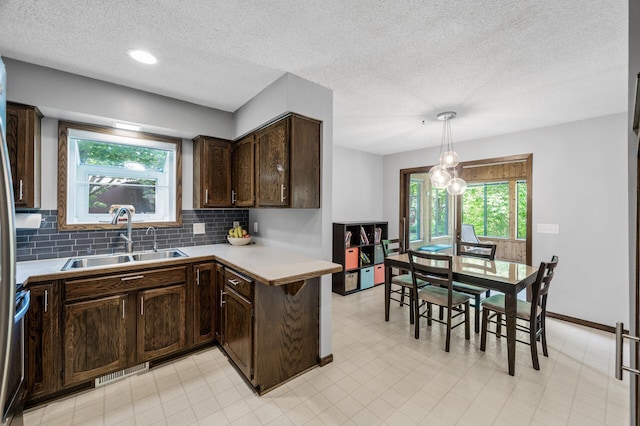 805 Ithaca Ln N, Plymouth, MN 55447 - kitchen with a sink, dark brown cabinetry, light countertops, decorative backsplash, and a textured ceiling