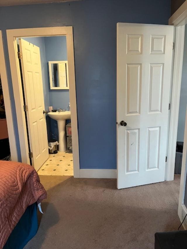 carpeted bedroom featuring baseboards and a sink