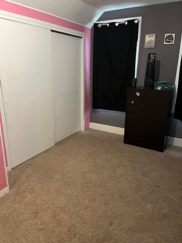 unfurnished bedroom featuring lofted ceiling, carpet, and a closet