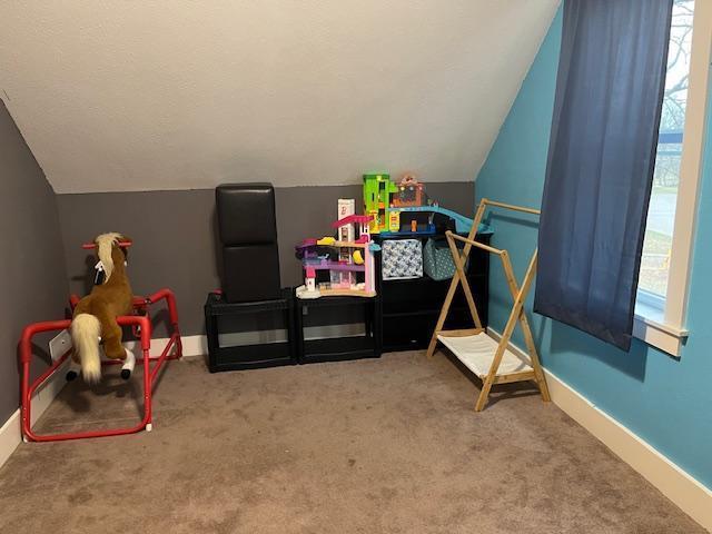recreation room with carpet, lofted ceiling, and baseboards