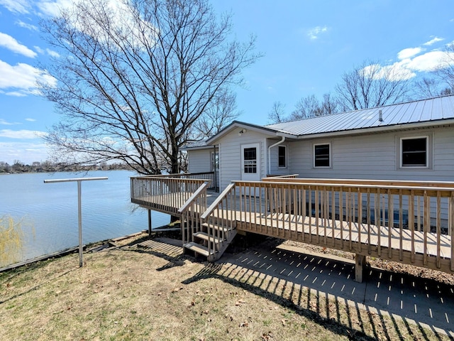 rear view of property featuring a deck with water view and metal roof