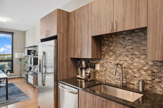 1240 2nd St Unit 526, Minneapolis, MN 55415 - kitchen featuring dark stone countertops, a baseboard radiator, appliances with stainless steel finishes, backsplash, and a sink