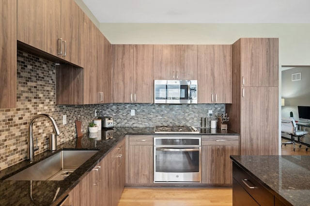 1240 2nd St Unit 526, Minneapolis, MN 55415 - kitchen featuring dark stone countertops, appliances with stainless steel finishes, backsplash, a sink, and visible vents