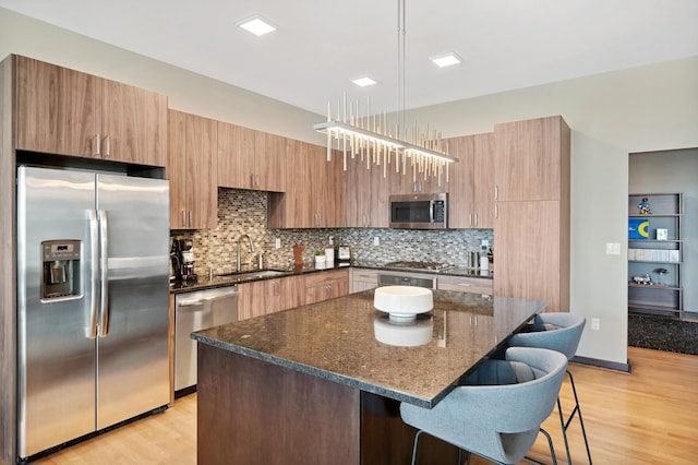 1240 2nd St Unit 526, Minneapolis, MN 55415 - kitchen featuring appliances with stainless steel finishes, backsplash, a sink, light wood-type flooring, and a kitchen breakfast bar