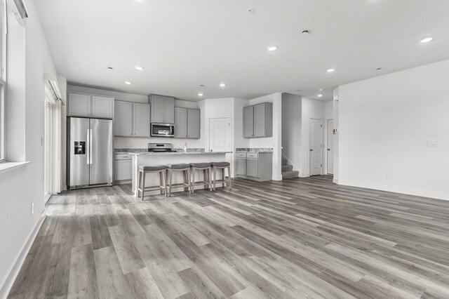 living area featuring stairway, baseboards, light wood-type flooring, and recessed lighting