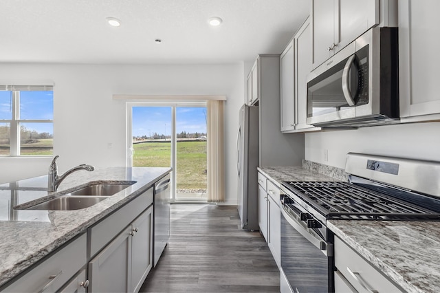 kitchen featuring light stone counters, a sink, stainless steel appliances, dark wood-style floors, and recessed lighting
