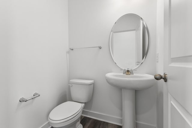 bathroom featuring wood finished floors, baseboards, and toilet