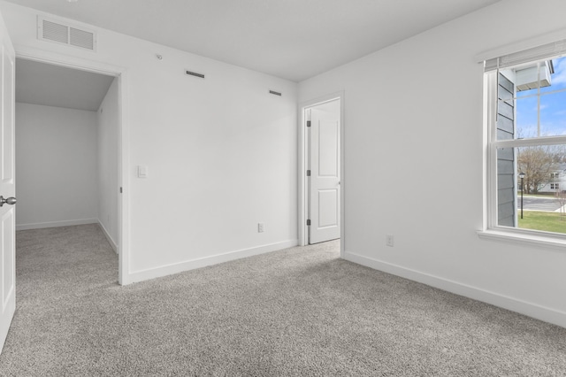 carpeted spare room with baseboards, visible vents, and a wealth of natural light