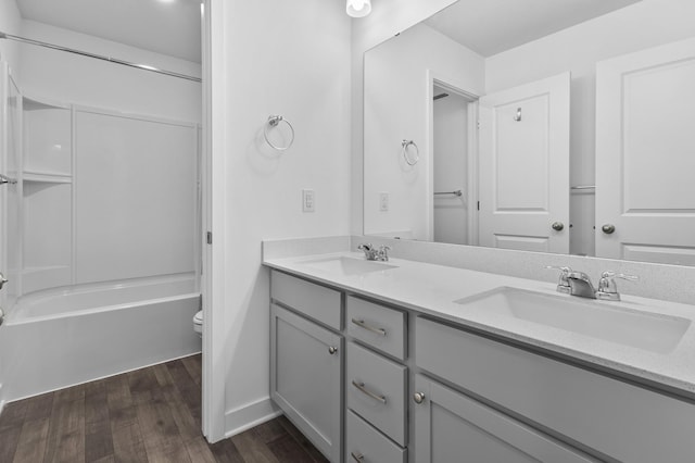 full bath featuring wood finished floors, a sink, double vanity, and toilet