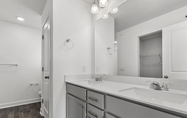 bathroom featuring double vanity, toilet, wood finished floors, and a sink