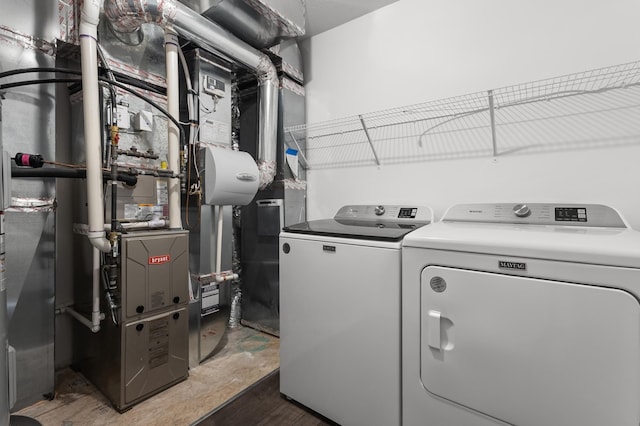 clothes washing area featuring washing machine and dryer, wood finished floors, and laundry area