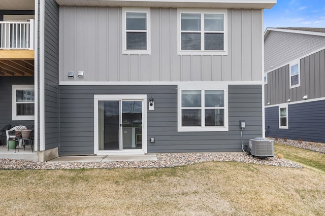 rear view of house with board and batten siding, a yard, central air condition unit, and a patio