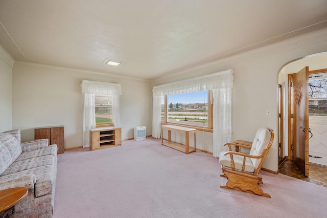 carpeted living room with arched walkways, baseboards, and a healthy amount of sunlight