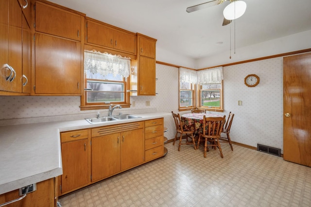 kitchen with a sink, light countertops, wallpapered walls, light floors, and visible vents