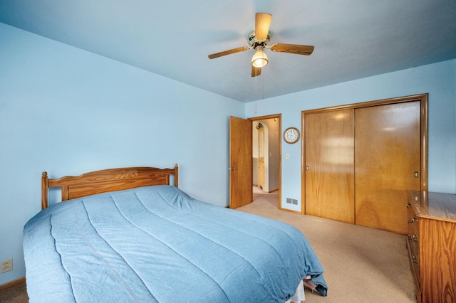bedroom with a closet, ceiling fan, visible vents, and light carpet