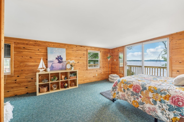 carpeted bedroom featuring wood walls, a water view, and access to exterior