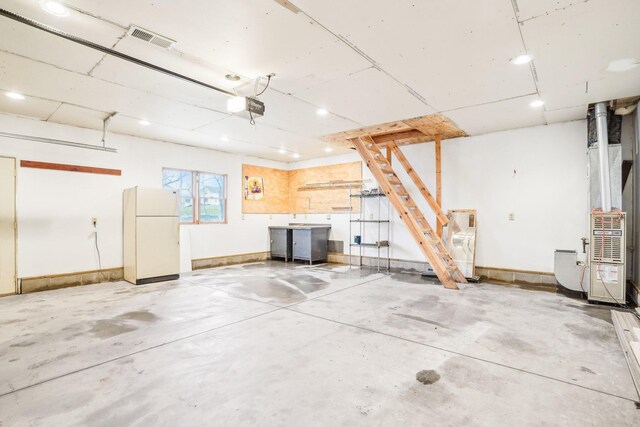 garage with visible vents, freestanding refrigerator, baseboards, recessed lighting, and a garage door opener