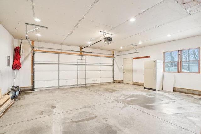 garage with baseboards, a garage door opener, and freestanding refrigerator