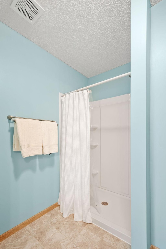 11215 16th St NE, Saint Michael, MN 55376 - bathroom with a textured ceiling, a shower with shower curtain, and baseboards