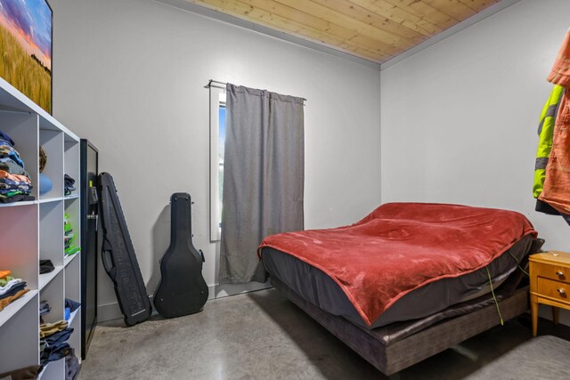bedroom with concrete flooring and wooden ceiling