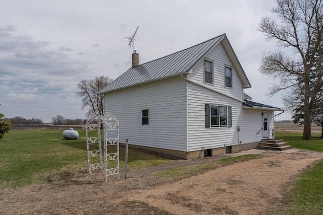 view of property exterior featuring a lawn, a chimney, a standing seam roof, and metal roof