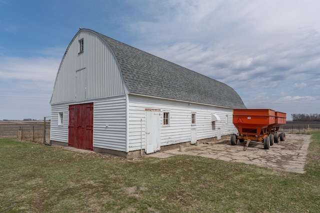 view of barn with fence and a yard