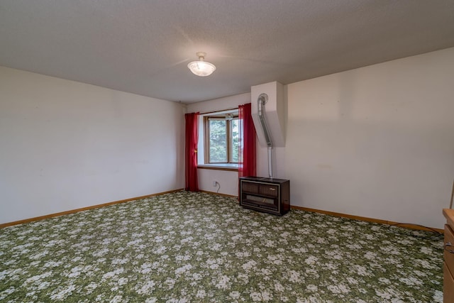 carpeted spare room featuring heating unit, baseboards, a textured ceiling, and a wood stove
