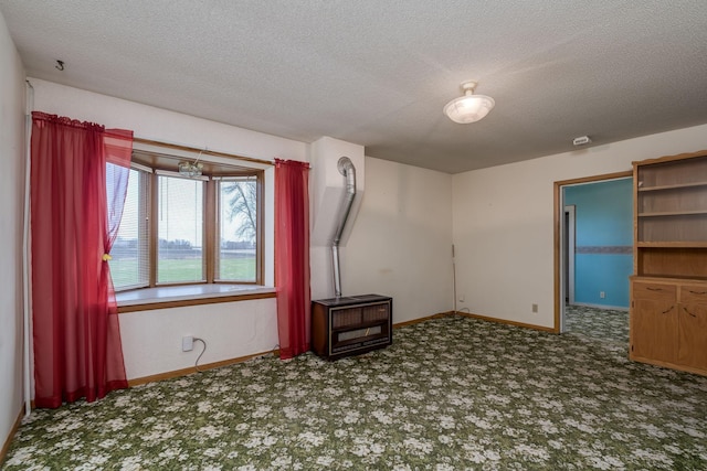 carpeted spare room featuring a textured ceiling and baseboards