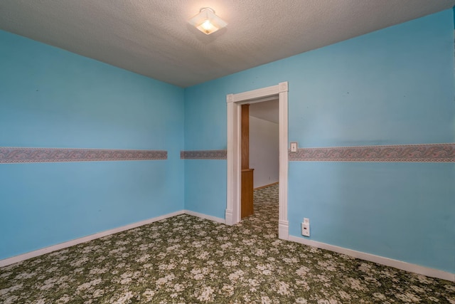 spare room featuring carpet floors, a textured ceiling, and baseboards