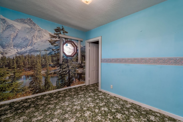 carpeted spare room featuring a water and mountain view, a textured ceiling, and baseboards