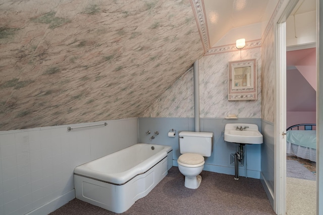 full bathroom featuring vaulted ceiling, a garden tub, a sink, wainscoting, and toilet